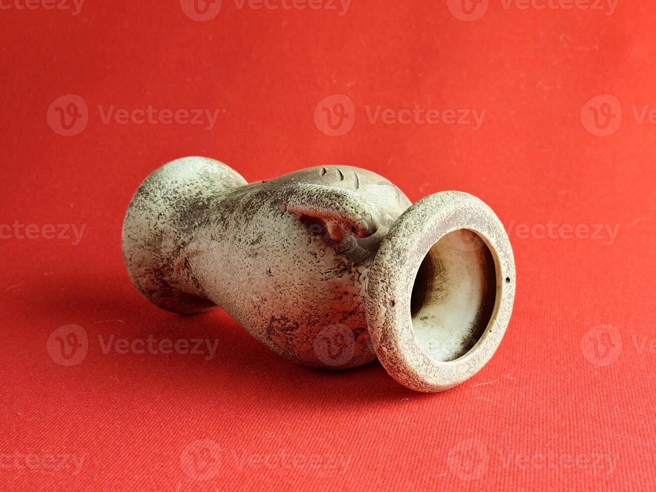 Antique ceramic decorative amphora on red background. The clay pot, set of antique utensils for gardening and interior photo