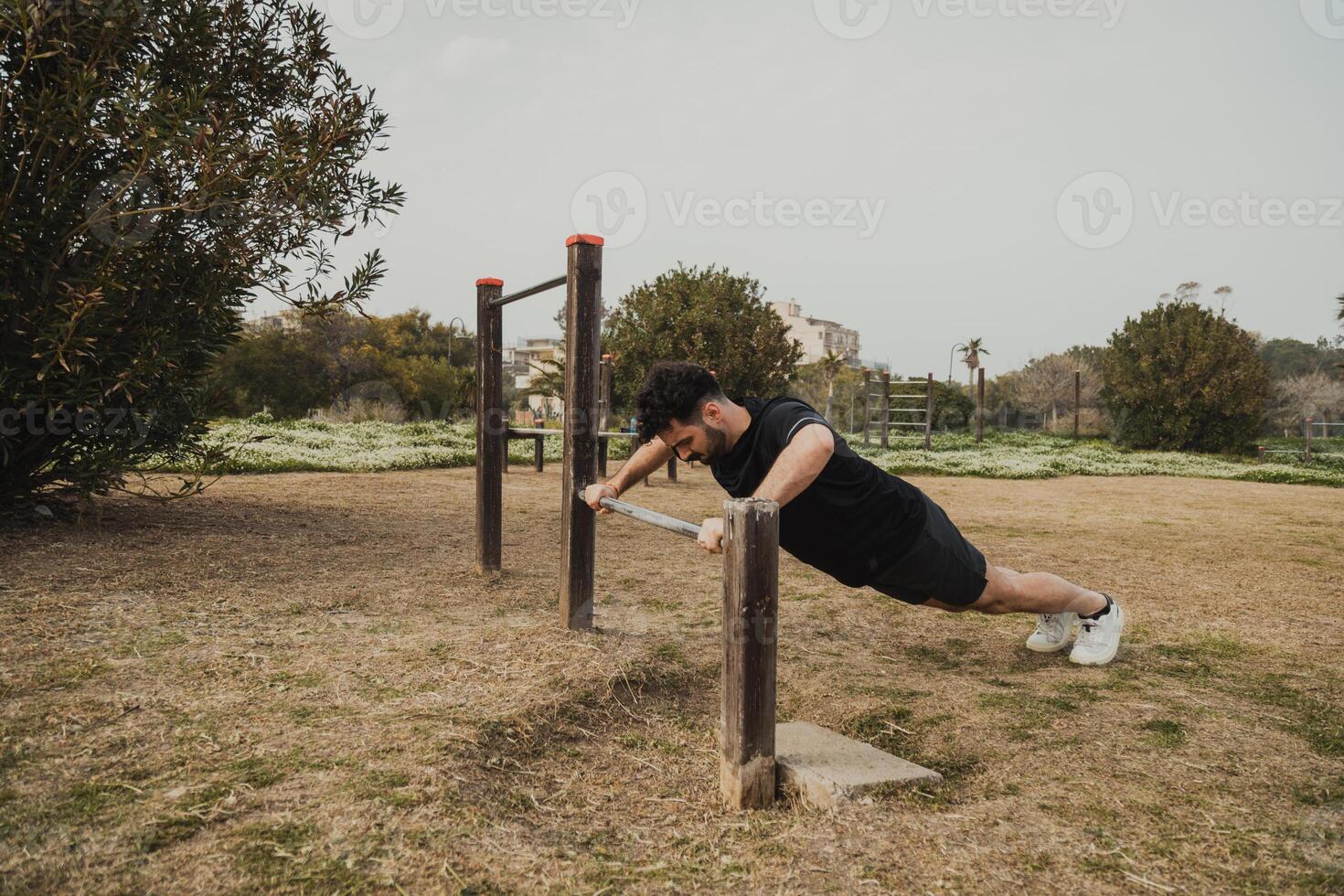 Man Does Push Ups Sport Exercise In The Park Using The Iron Bar Outside photo