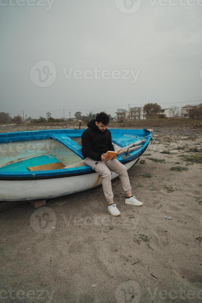 Man Reads A Book In Solitude By The Sea On A Gloomy Day Outdoor photo