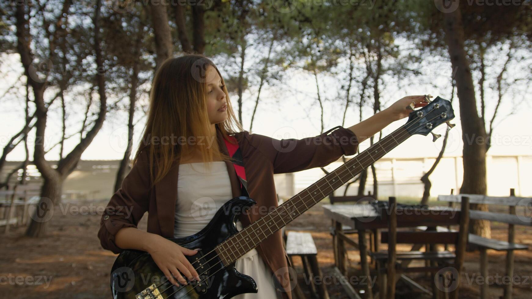 Girl Handles To Tune Bass Musical Instrument In The Park Outdoor photo