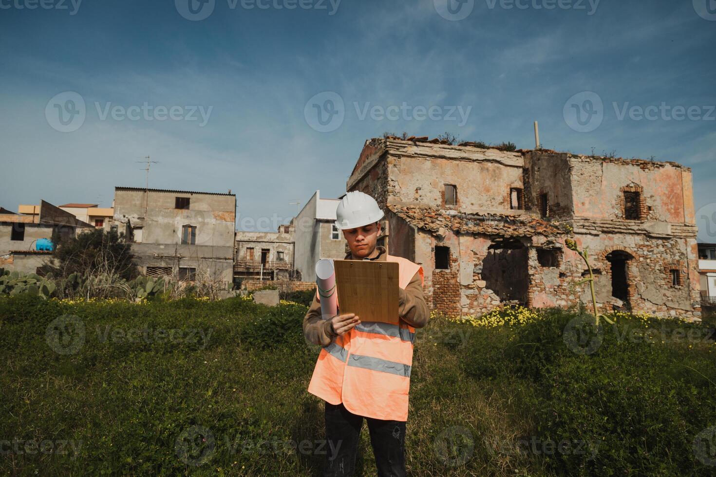 Engineer On The Construction Site Looking At The Ruined Building And Taking Notes photo