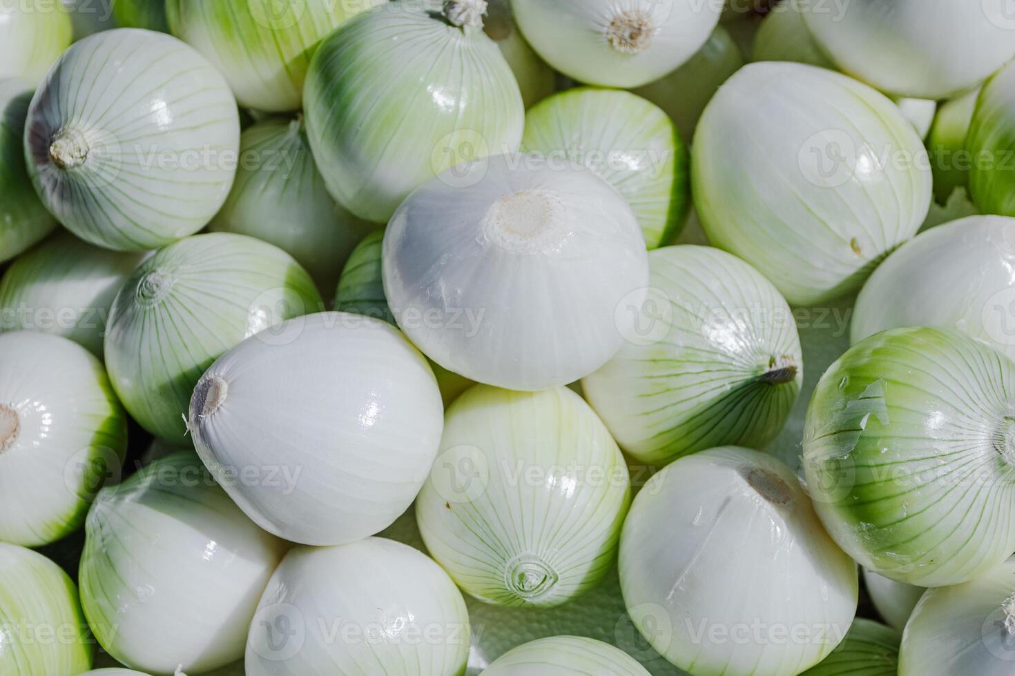 A close-up of fresh onions in a woven basket under hard natural light. The intense shadows and highlights emphasize the rough texture and organic layers, ideal for food styling and culinary content photo