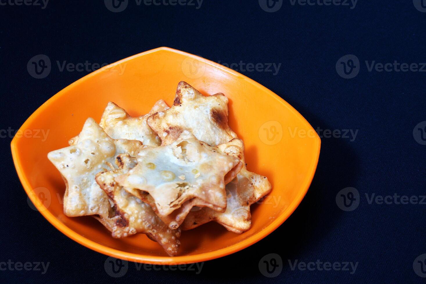 A bowl of Aloo Puff Pastry topped with a star-shaped design and served with tomato sauce. photo