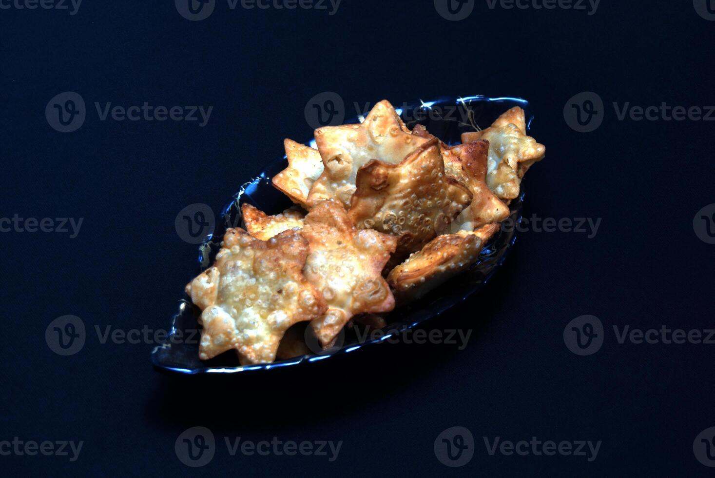 A glass bowl filled with deliciously fried chicken wings, elegantly presented with a vibrant tomato sauce on the side. photo
