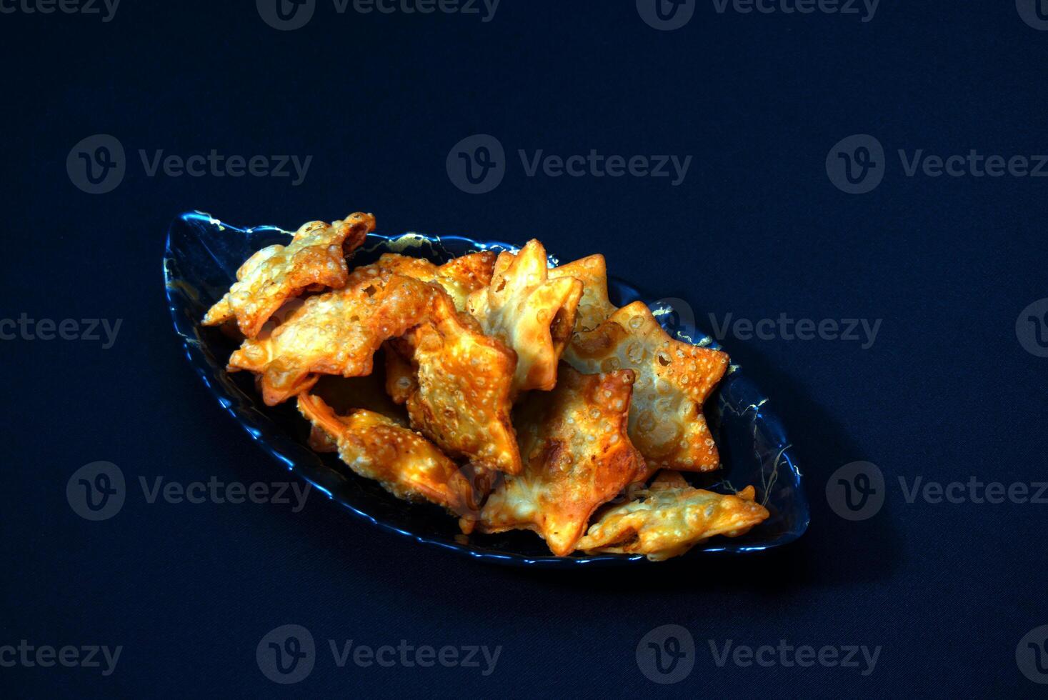 A clear glass bowl filled with golden-brown fried chicken wings, served with a rich tomato sauce for dipping. photo