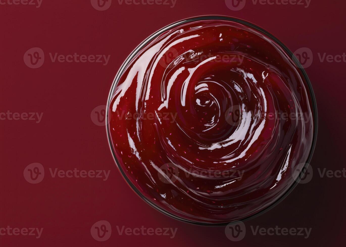 Red berry jam in glass bowl, top view, red background, copy space photo