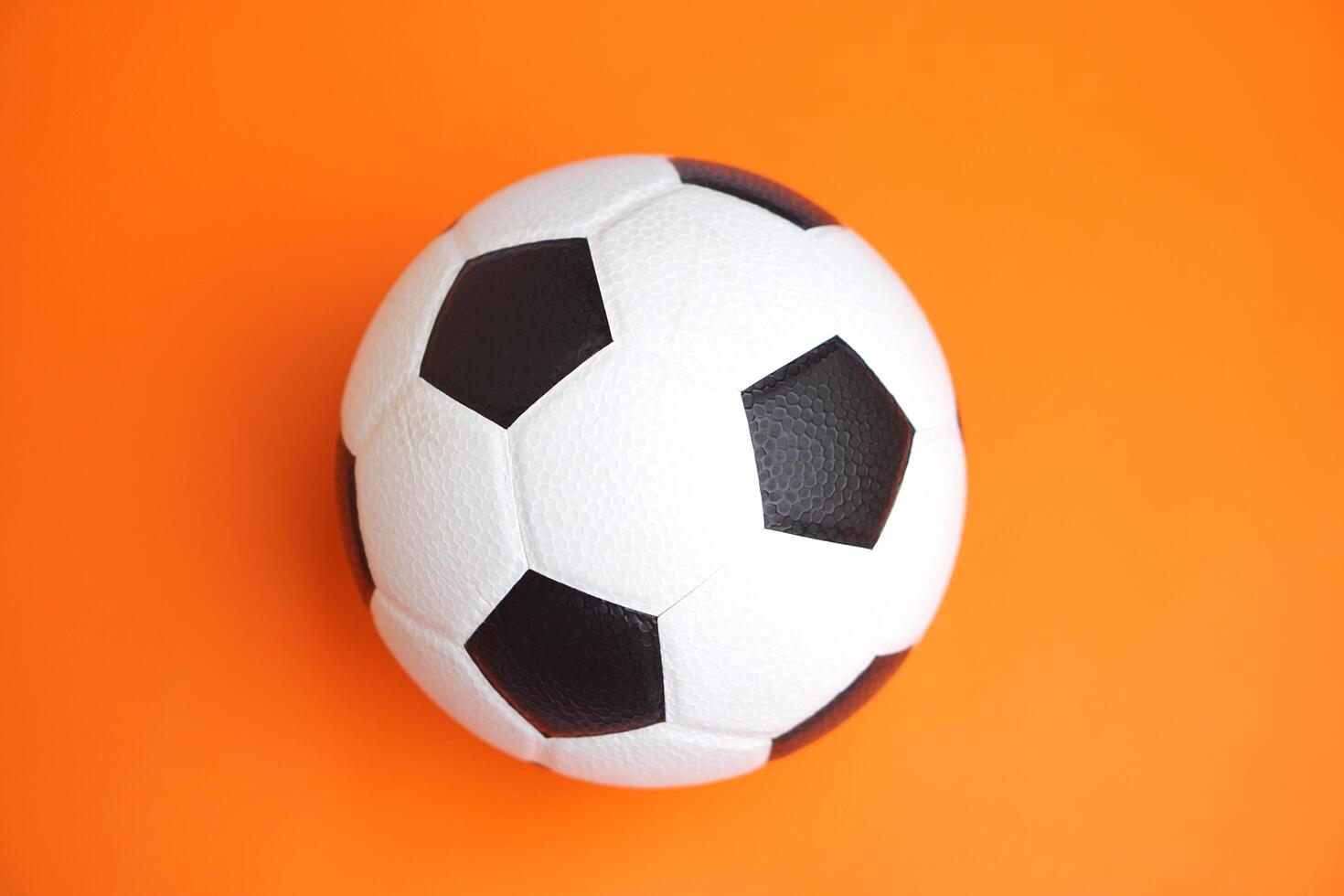 Football, soccer ball on orange background. Concept,sport equipment,symbol of energy, teamwork, and fitness. Ideal for promoting active lifestyle, workout, health, and football-related content. photo
