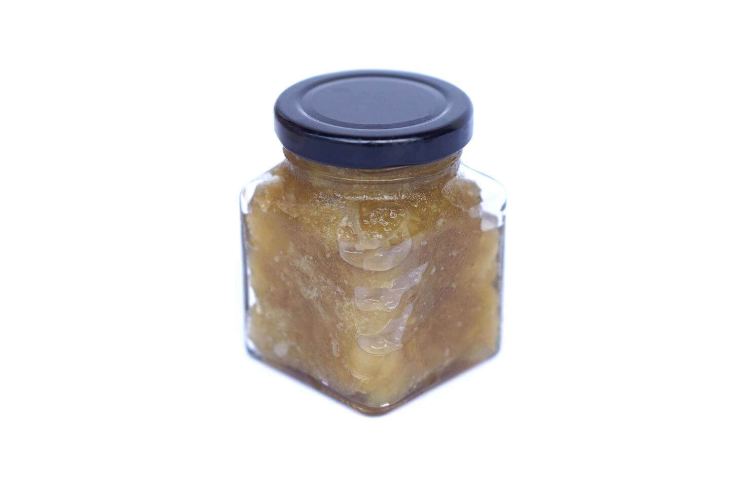 Glass jar of homemade mango jam in natural color, isolated on white background. Concept, fruit processing and food preservation,reducing food waste and extending shelf life naturally. photo