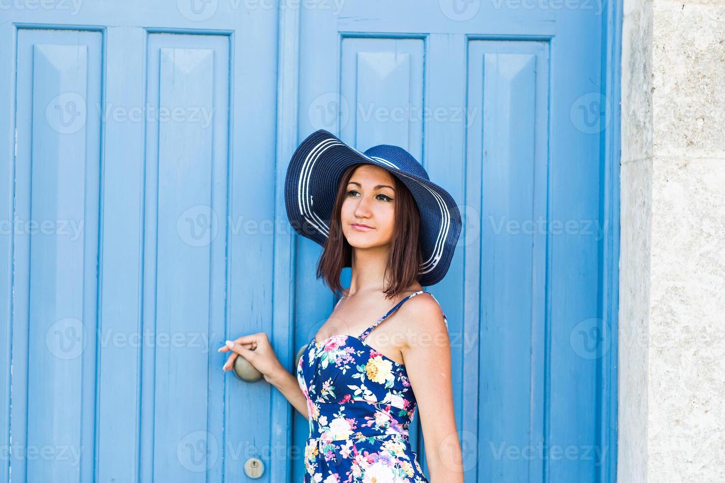 Young beautiful woman standing in front of a blue vintage entrance door photo