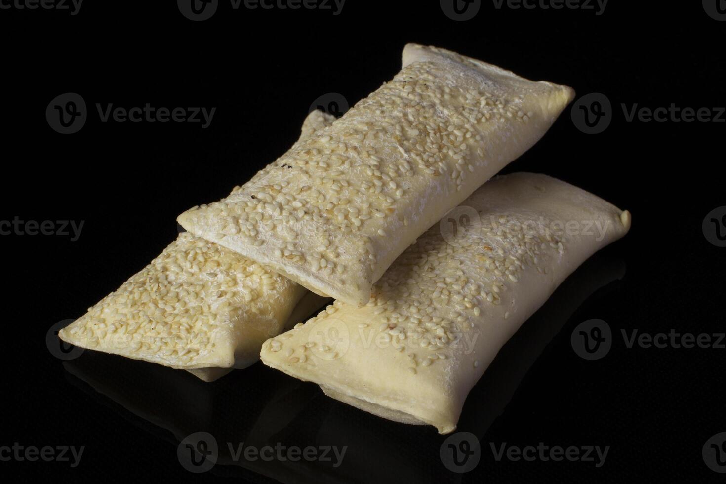 Semi-finished puff pastry with sesame seeds. Baking for baking on a black background photo