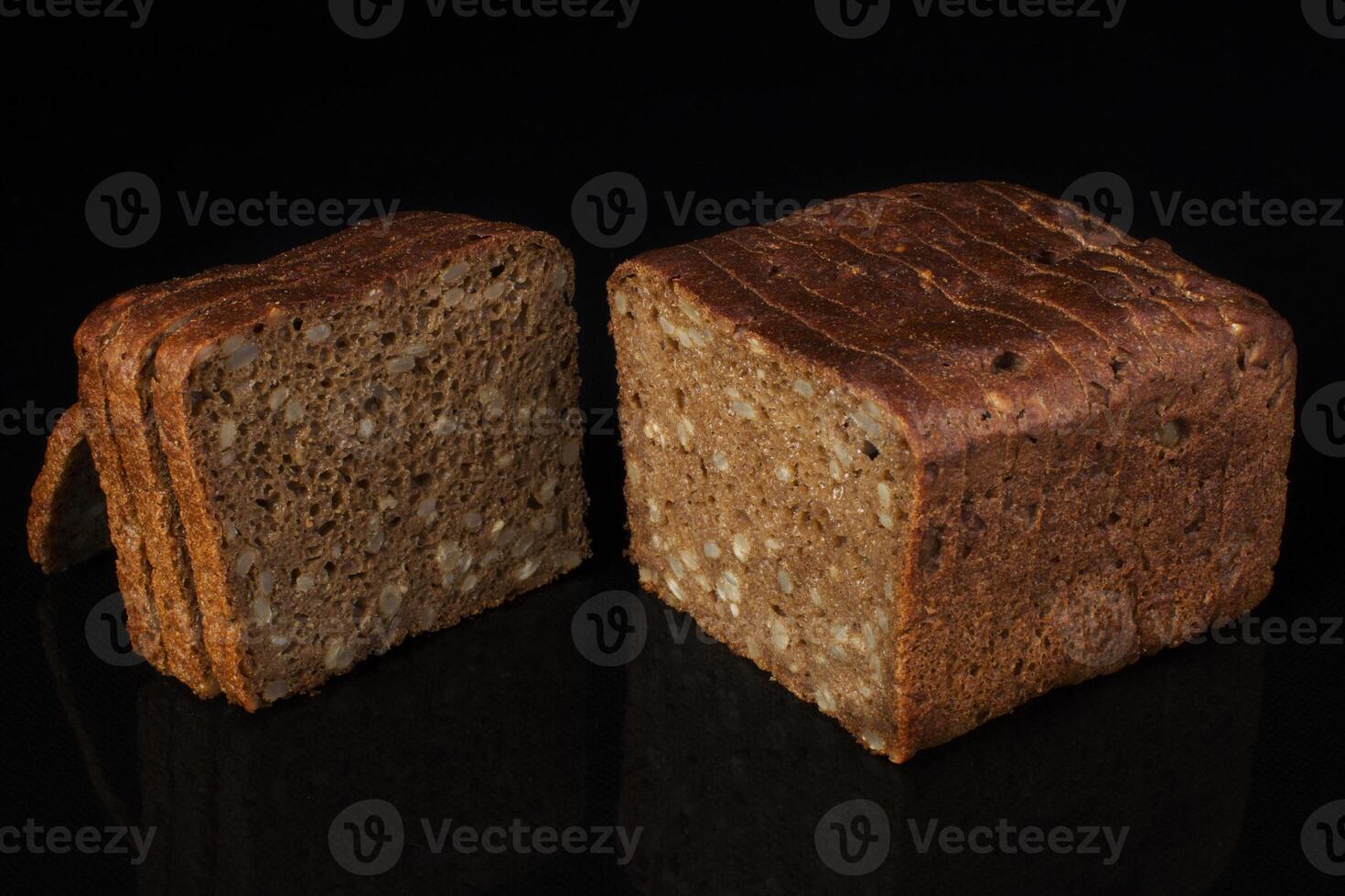 Ordinary bread with grains and sesame cut into pieces on a black background. Whole wheat bread photo