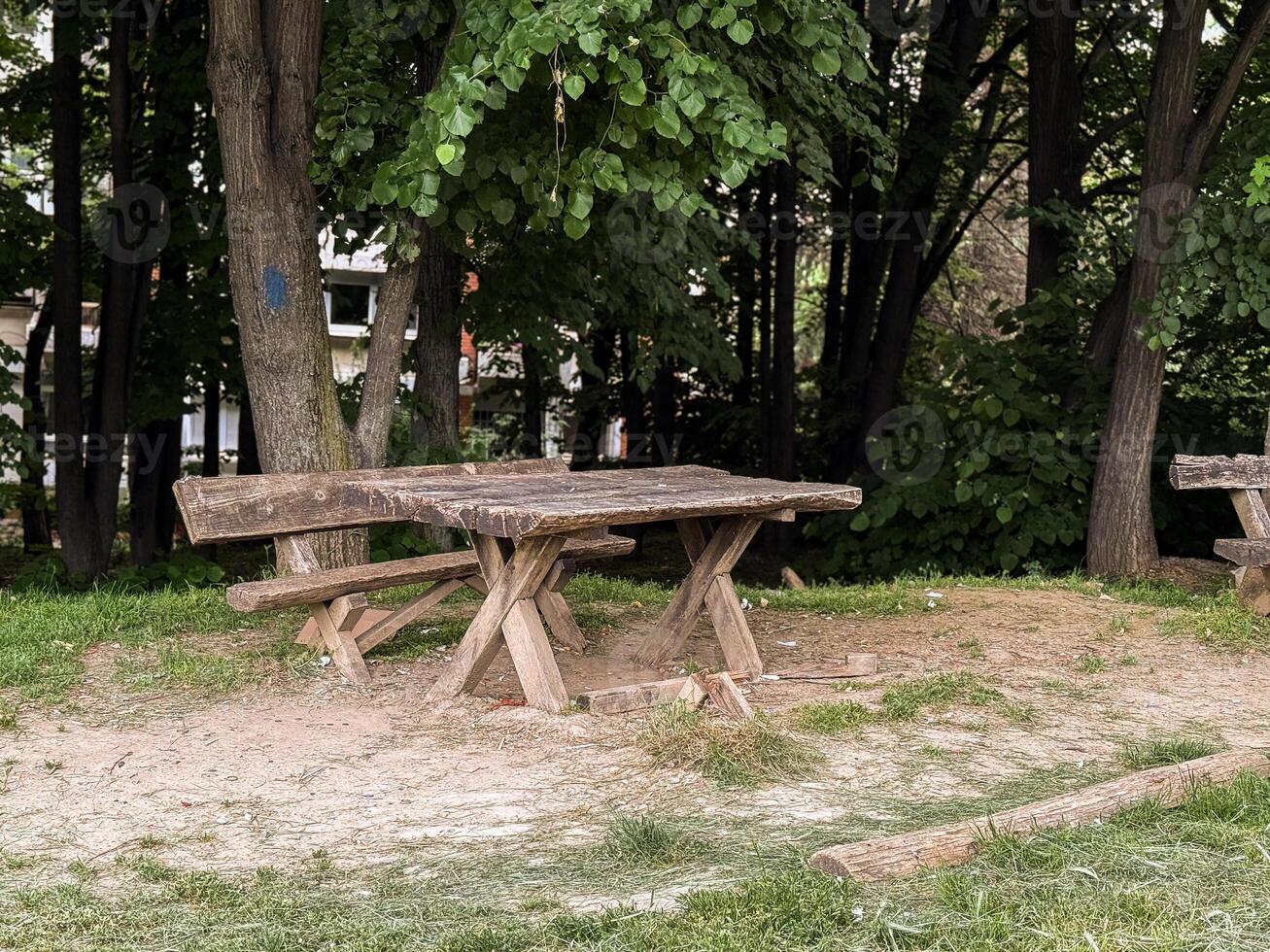 Old wooden picnic bench in a shaded forest clearing. A quiet corner in nature for rest and conversation. photo