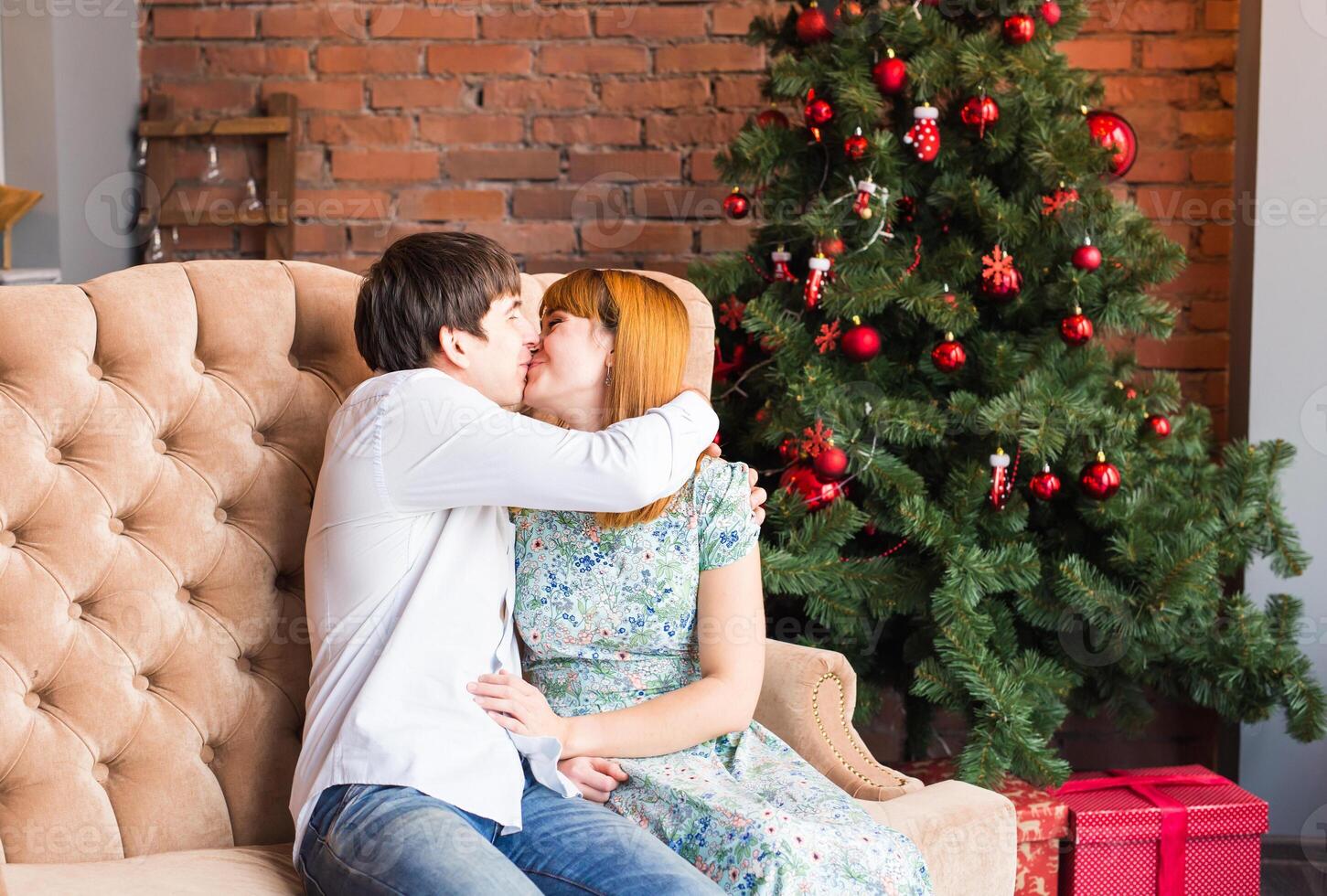 winter, love, couple, christmas and people concept - man and woman kissing over christmas tree background photo