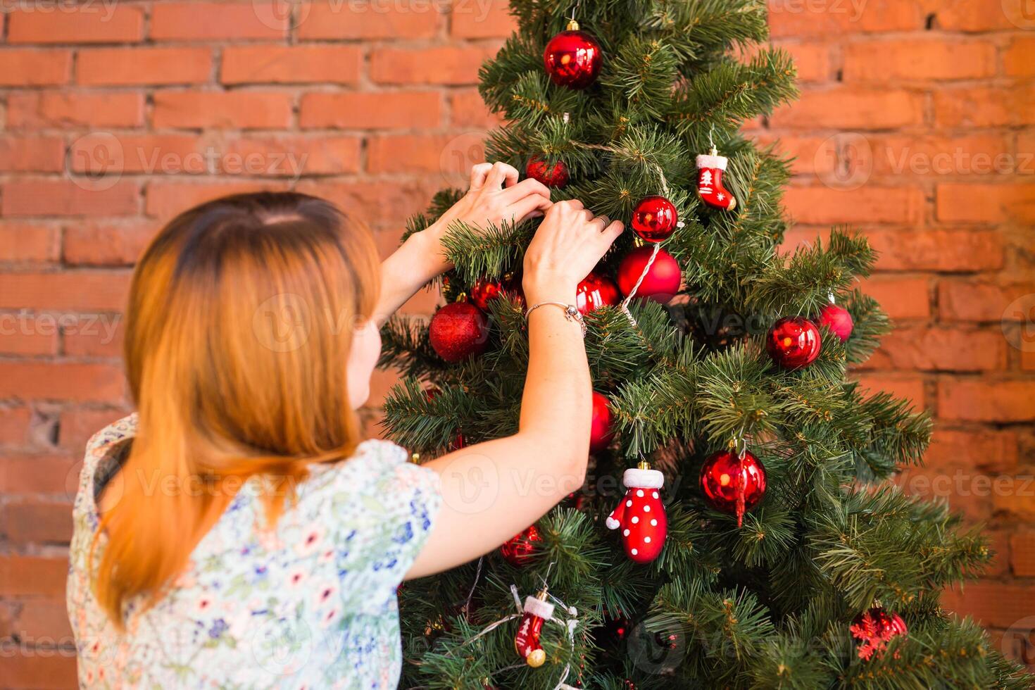 winter holidays, celebration and people concept - woman decorating christmas tree with ball photo