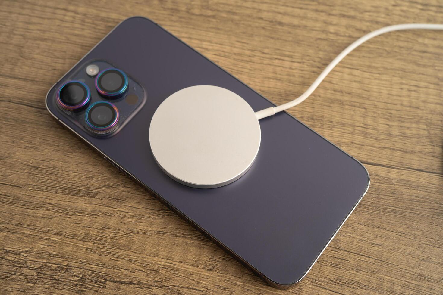 Bangkok, Thailand, January 10, 2024 Wireless charger on mobile phone, magnetic charging modern equipment of mobile phone. photo