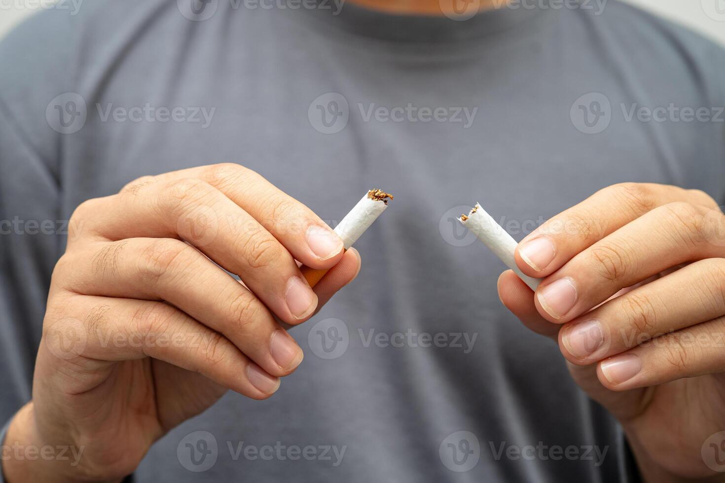 Quit smoking Asian teenage man breaking destroy cigarette in hand. photo