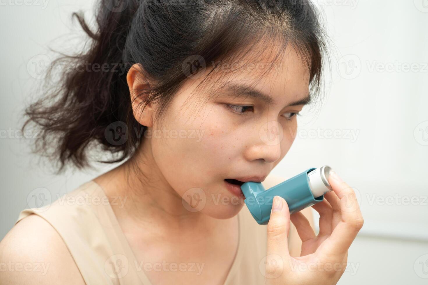 Asthma and chronic obstructive pulmonary disease COPD, Asian woman using metered dose inhaler MDI. photo