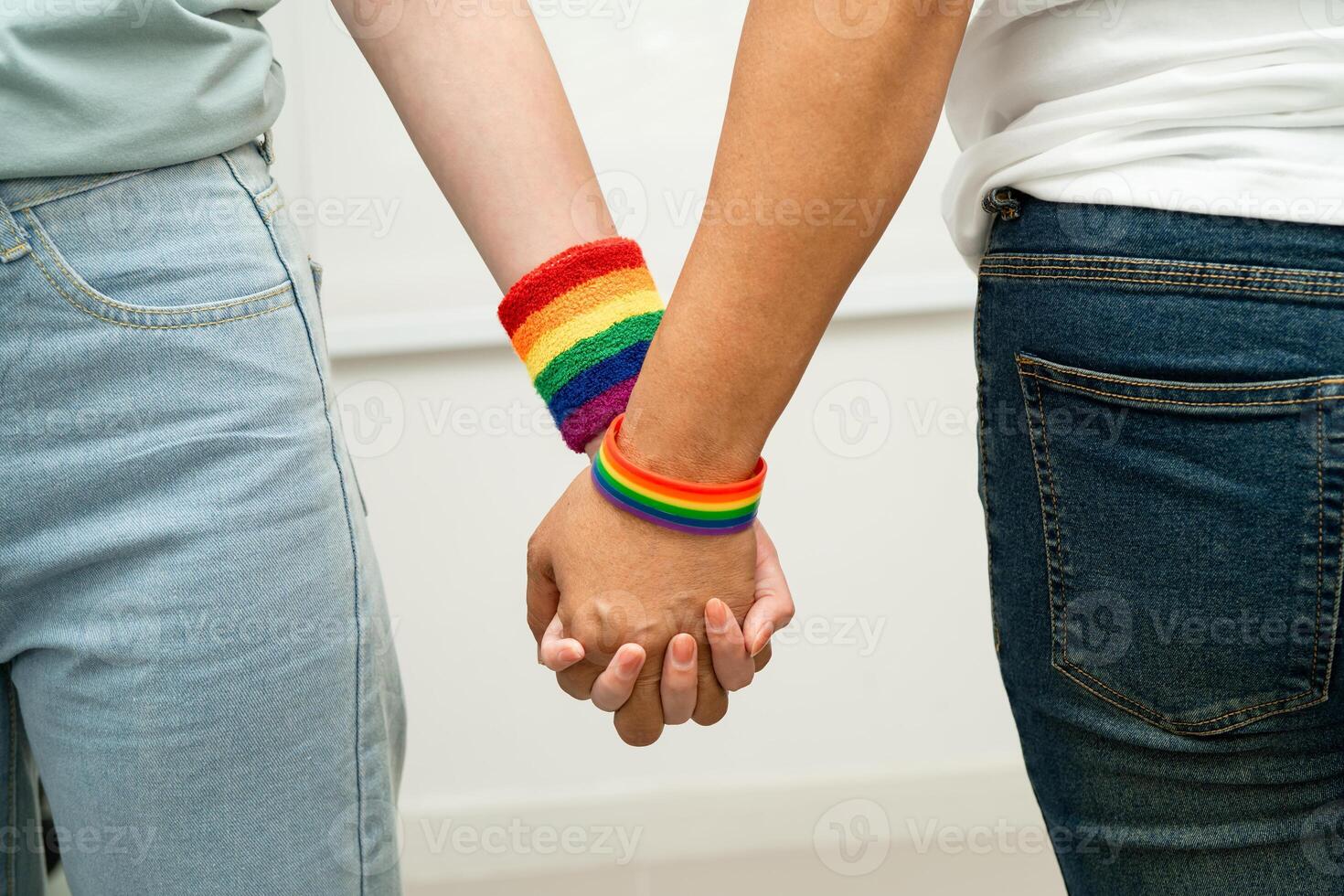LGBT couple holding hand wearing rainbow wristband. photo
