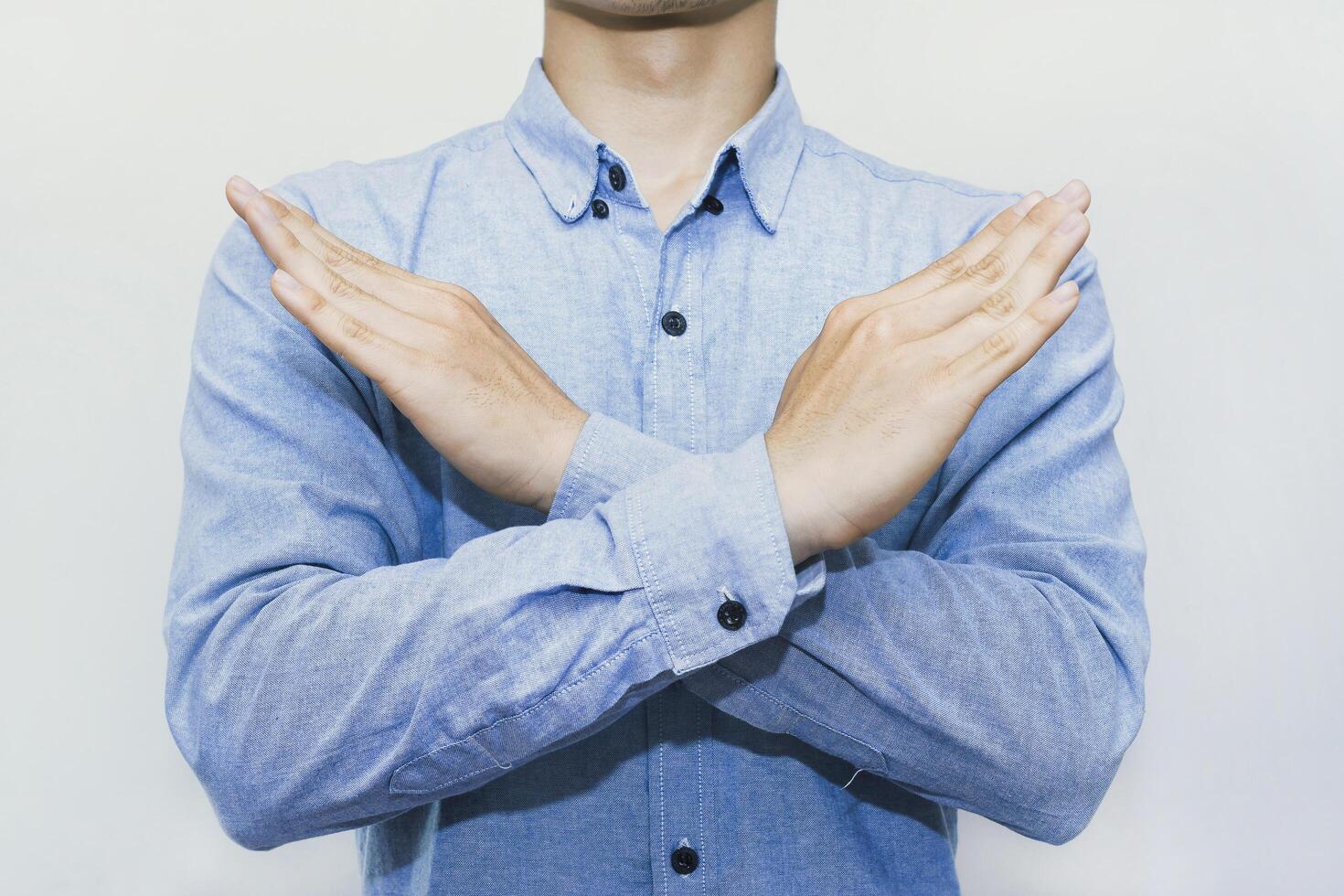 Man crossing arms in X gesture for stop, deny, protest, block, avoid, no access, restriction, warning, barrier, privacy, personal boundary, control, signal, disagreement. Isolated on white background. photo