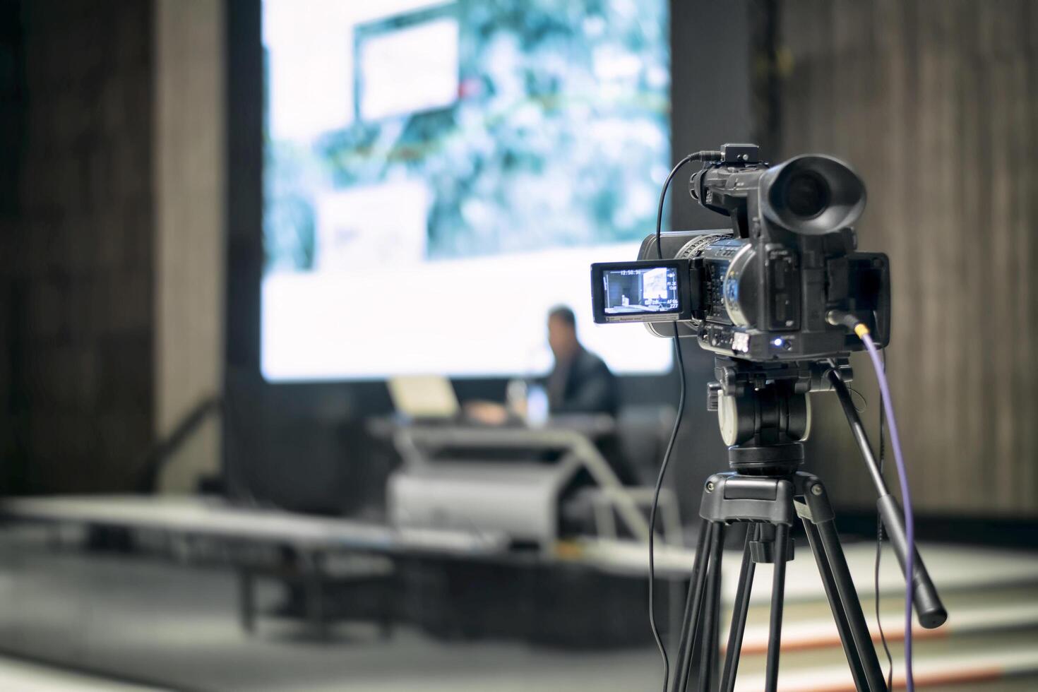 Professional camera on tripod recording a live event in a studio setting. Suitable for media production, digital content creation, broadcasting, education, and business presentations. photo
