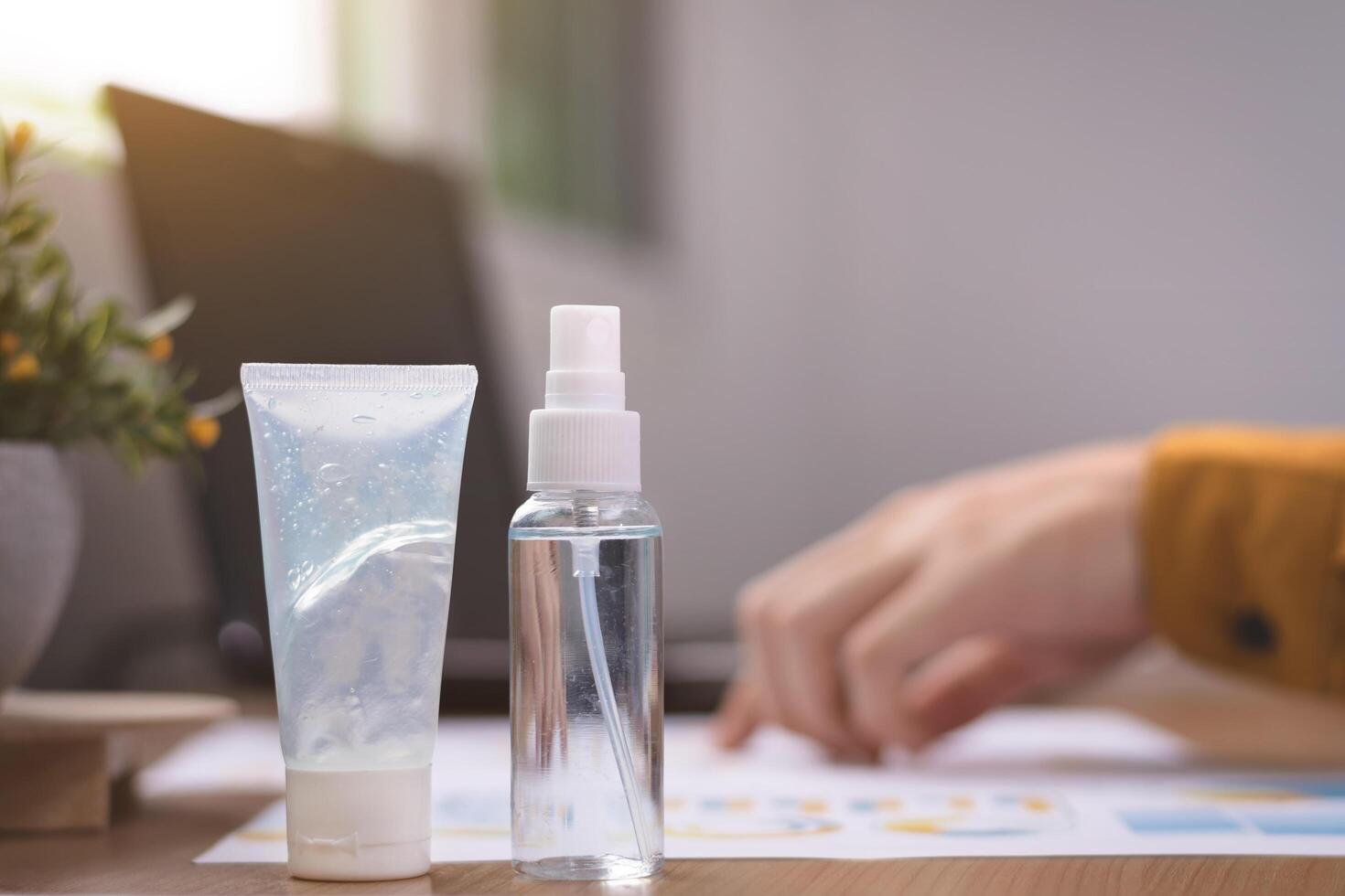 Hand sanitizer bottle on office desk with documents and laptop promotes hygiene, disinfection, and health protection. Emphasizes safety, cleanliness, daily wellness in personal or business workspace. photo