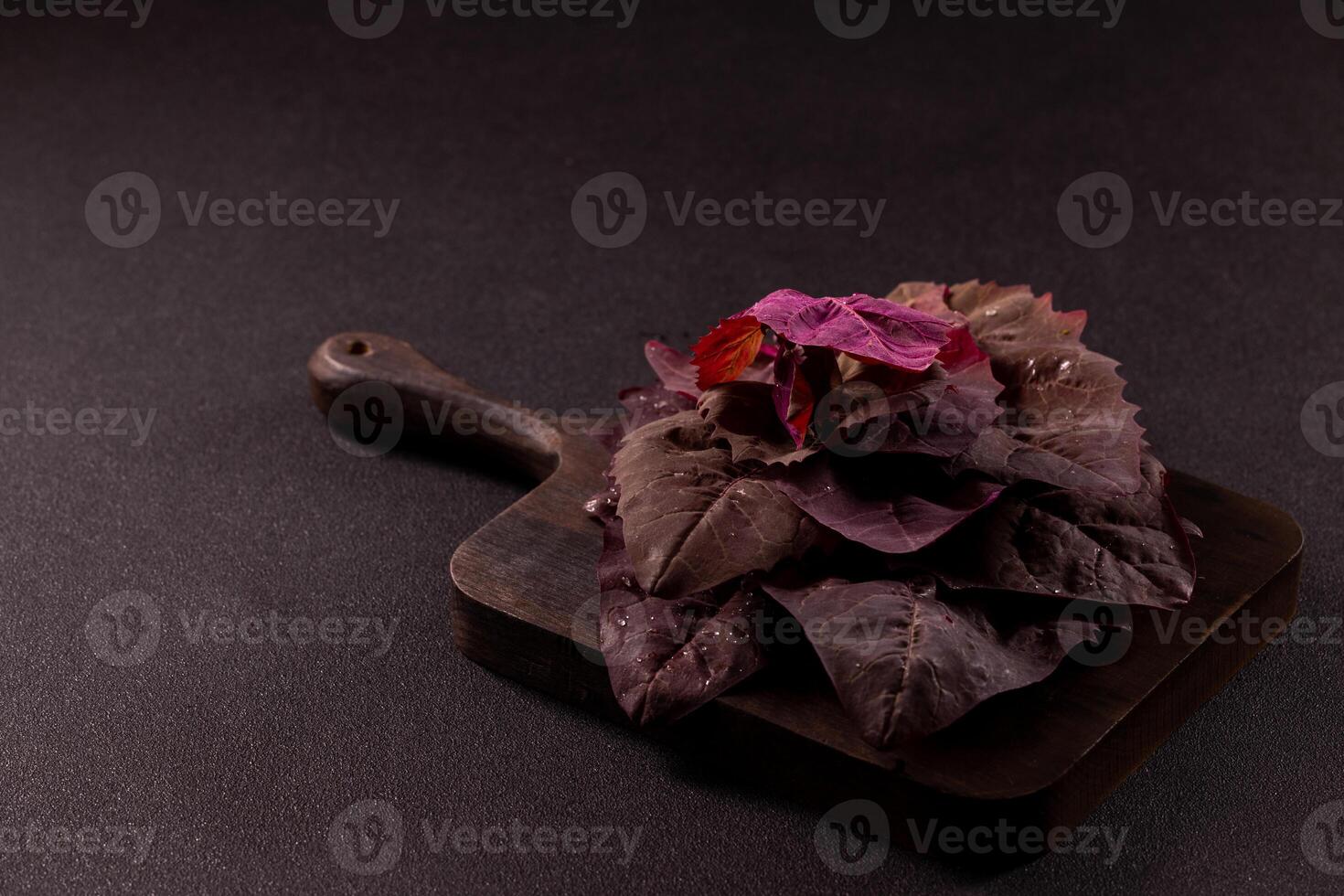 Fresh red spinach leaves resting on rustic wooden cutting board photo