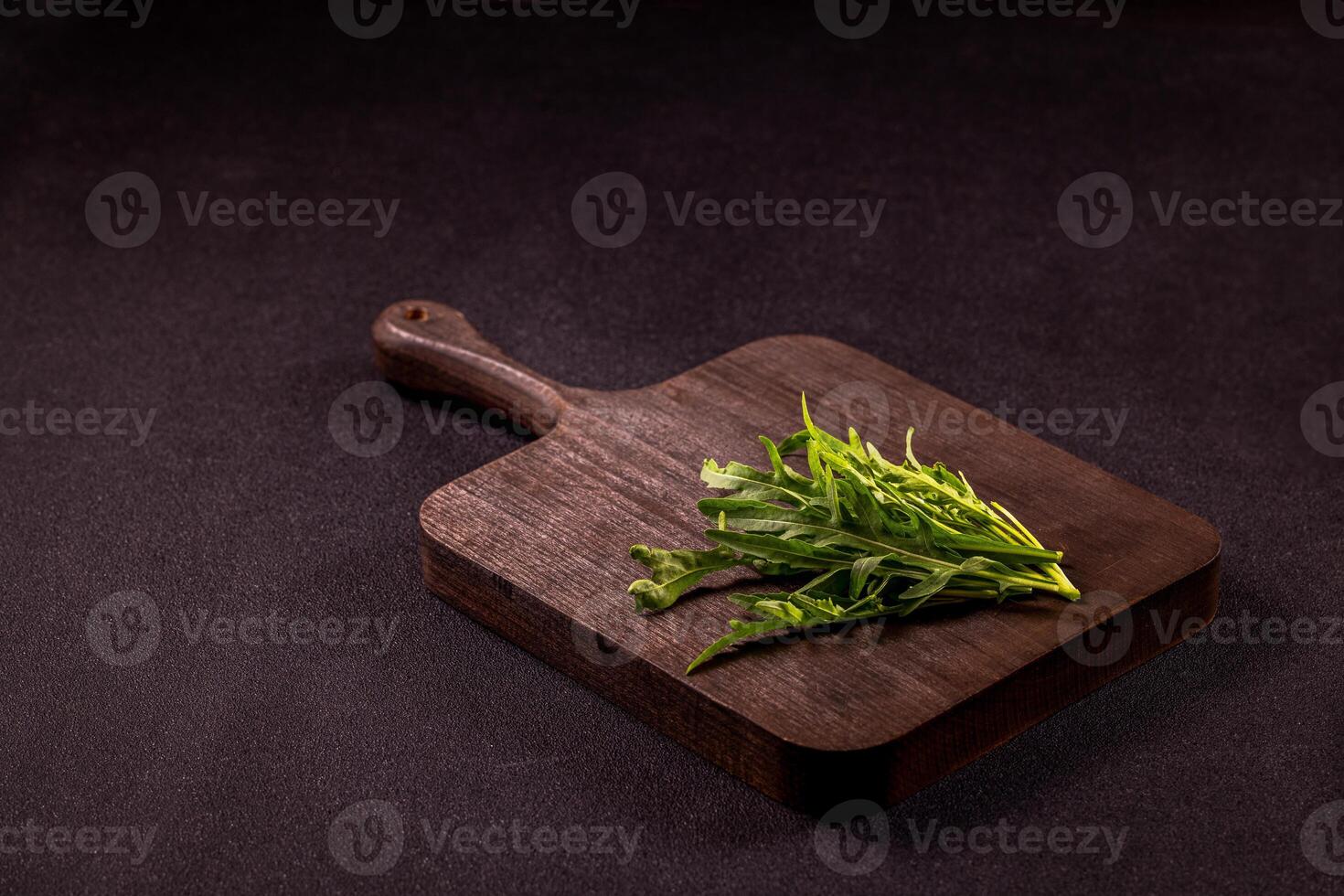 Fresh arugula leaves resting on rustic wooden cutting board, perfect for culinary creations photo