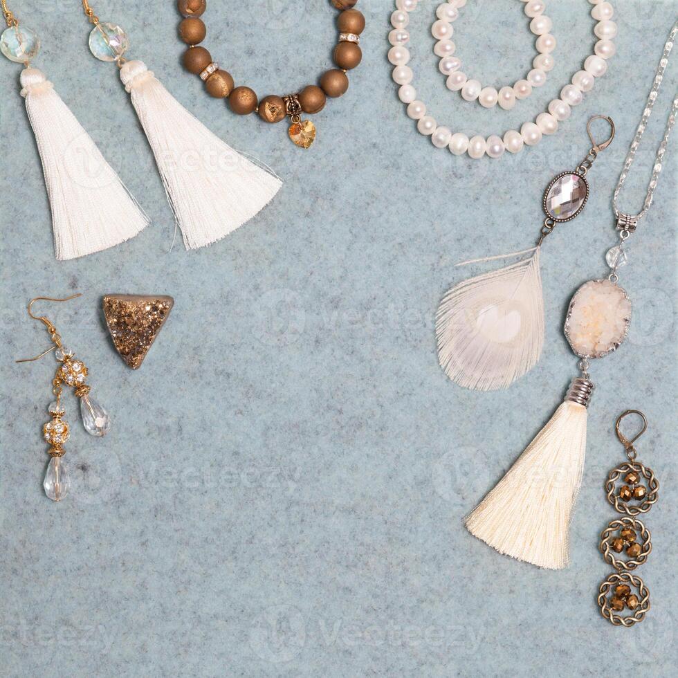 Handmade white and bronze jewelry on the gray woolen background photo
