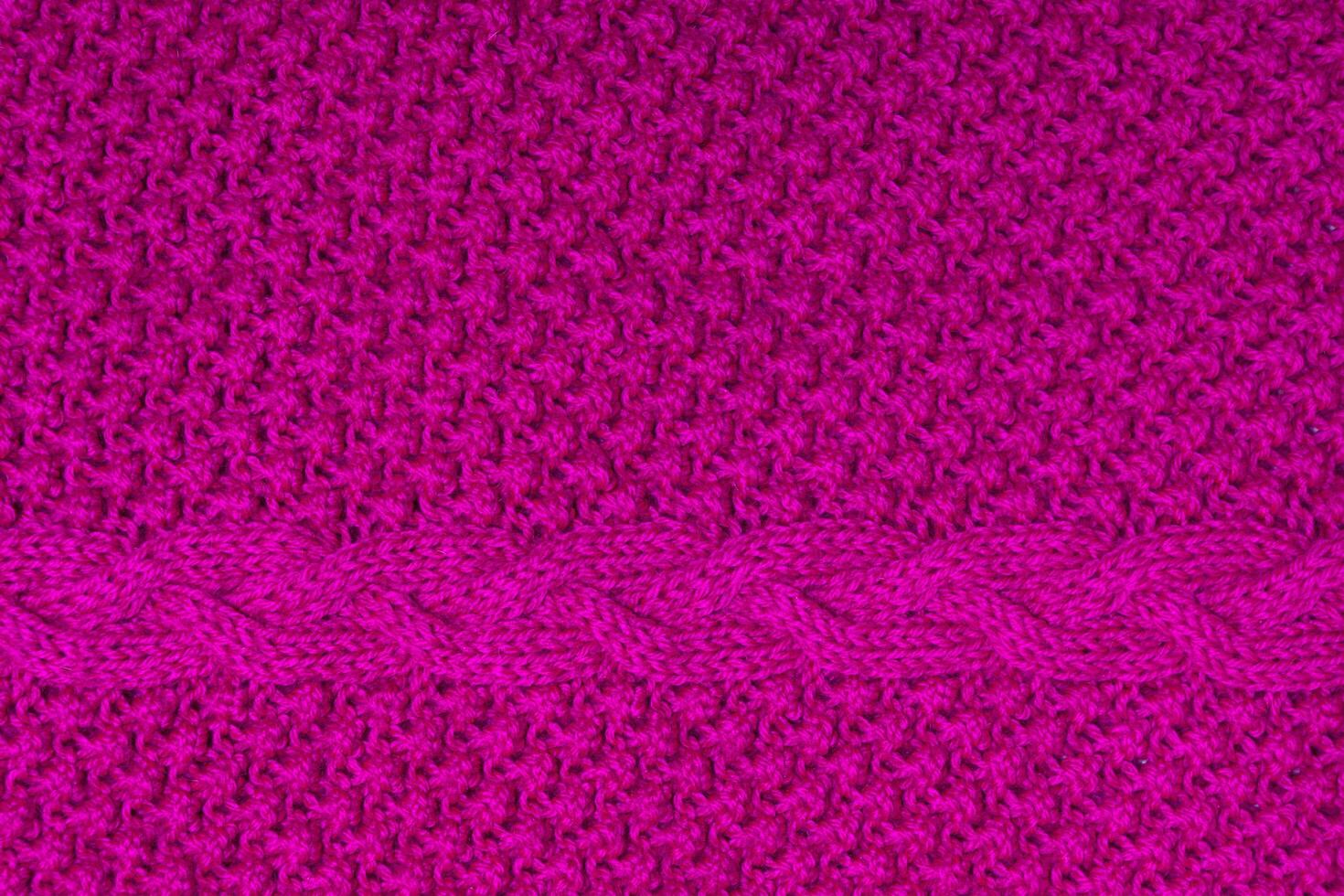 Top view of handmade bright fuchsia knitted texture with plait photo