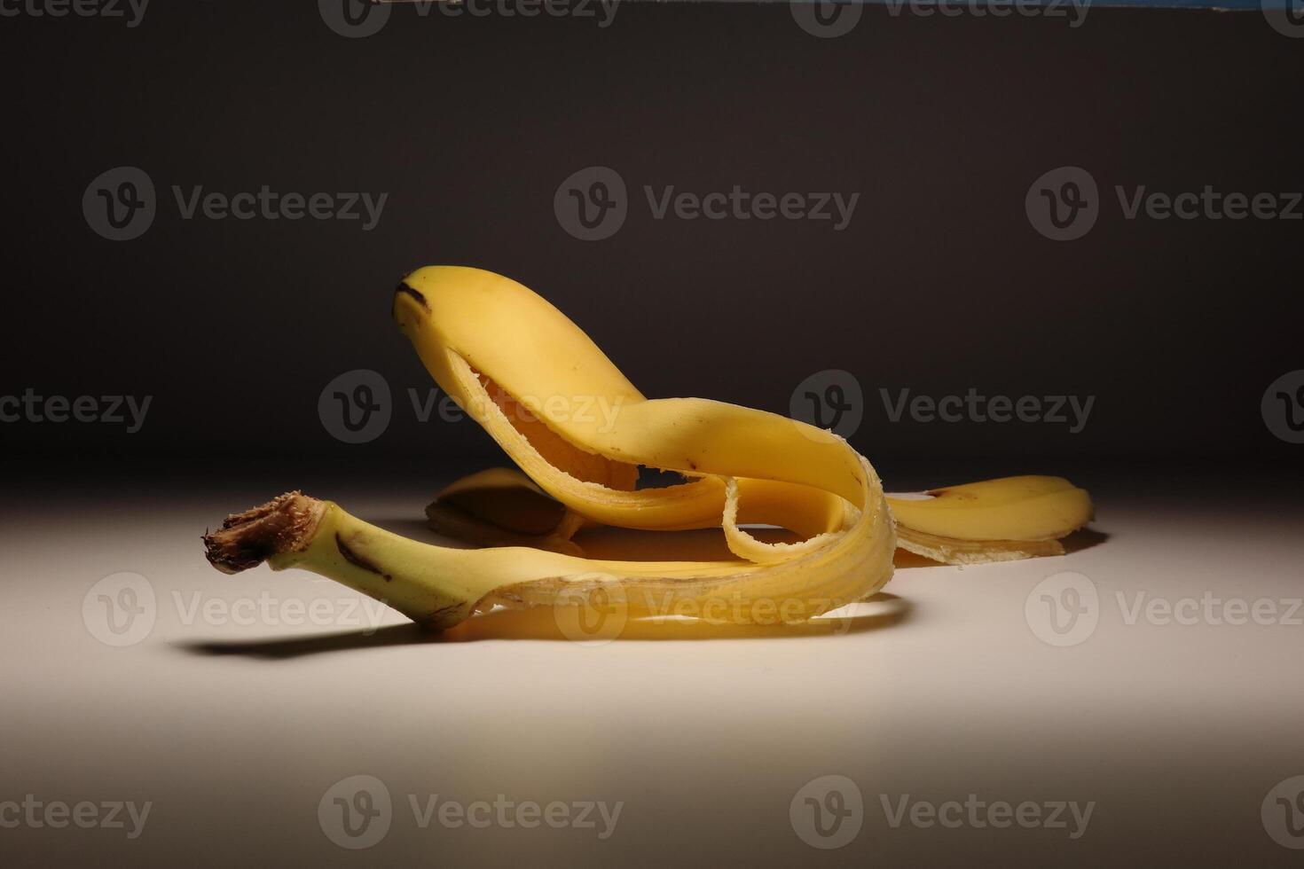 Single peeled banana on clean minimal background in studio lighting photo