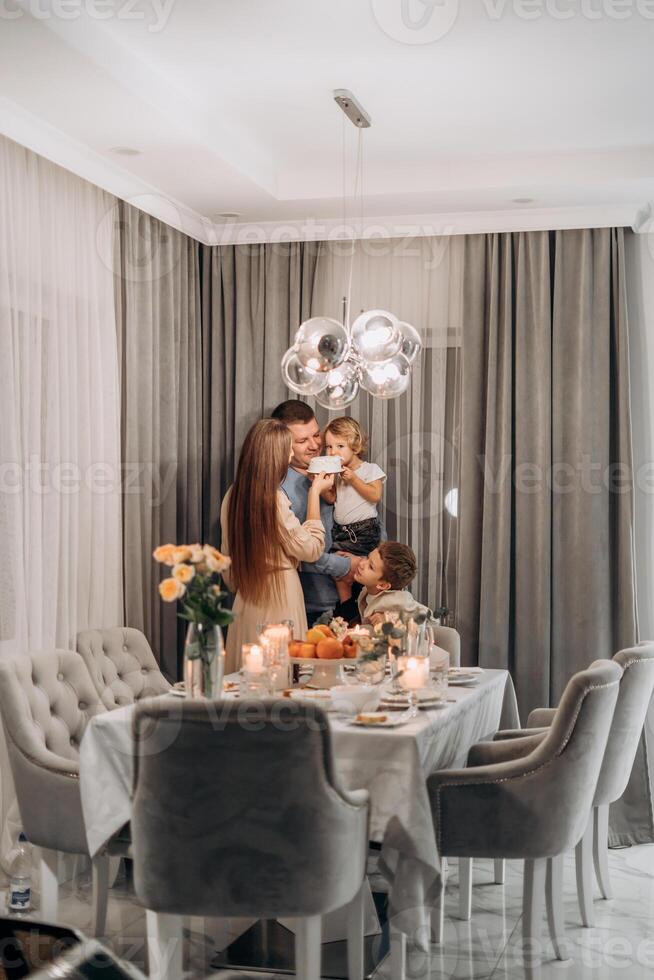 Smiling parents holding little child biting into white frosted cake while older brother watches with joy during sweet candid moment of family bonding celebration filled with warmth laughter and photo