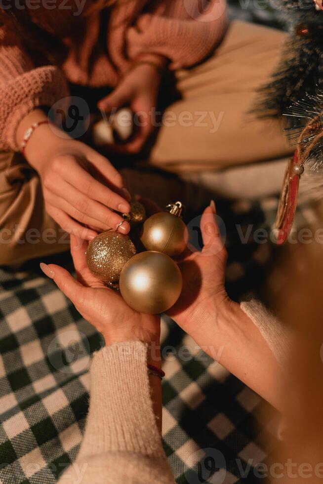 Close-up of hands gently holding golden Christmas ornaments during a quiet evening family ritual of decorating a tree with warm connection and thoughtful seasonal gestures Exchanging Christmas photo