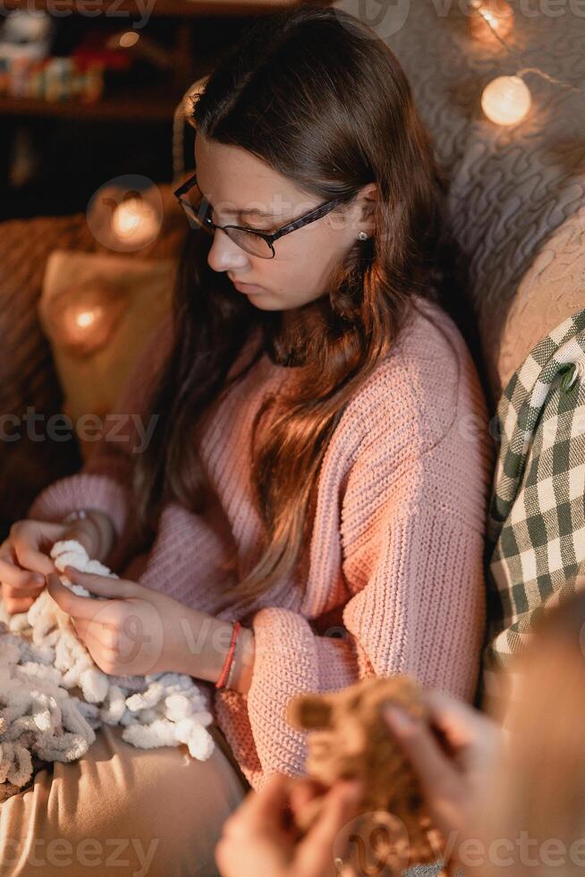A peaceful winter moment showing a teen girl deeply focused on her holiday handcraft using fluffy yarn in a warmly lit room with soft lights textures and mindful calm atmosphere photo
