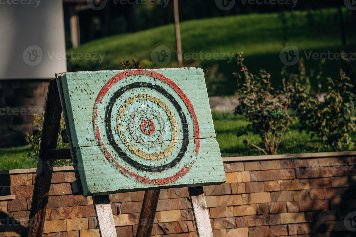 Close up view of dart holes on board due to throwing darts a bunch of times, outdoors, sunlight photo