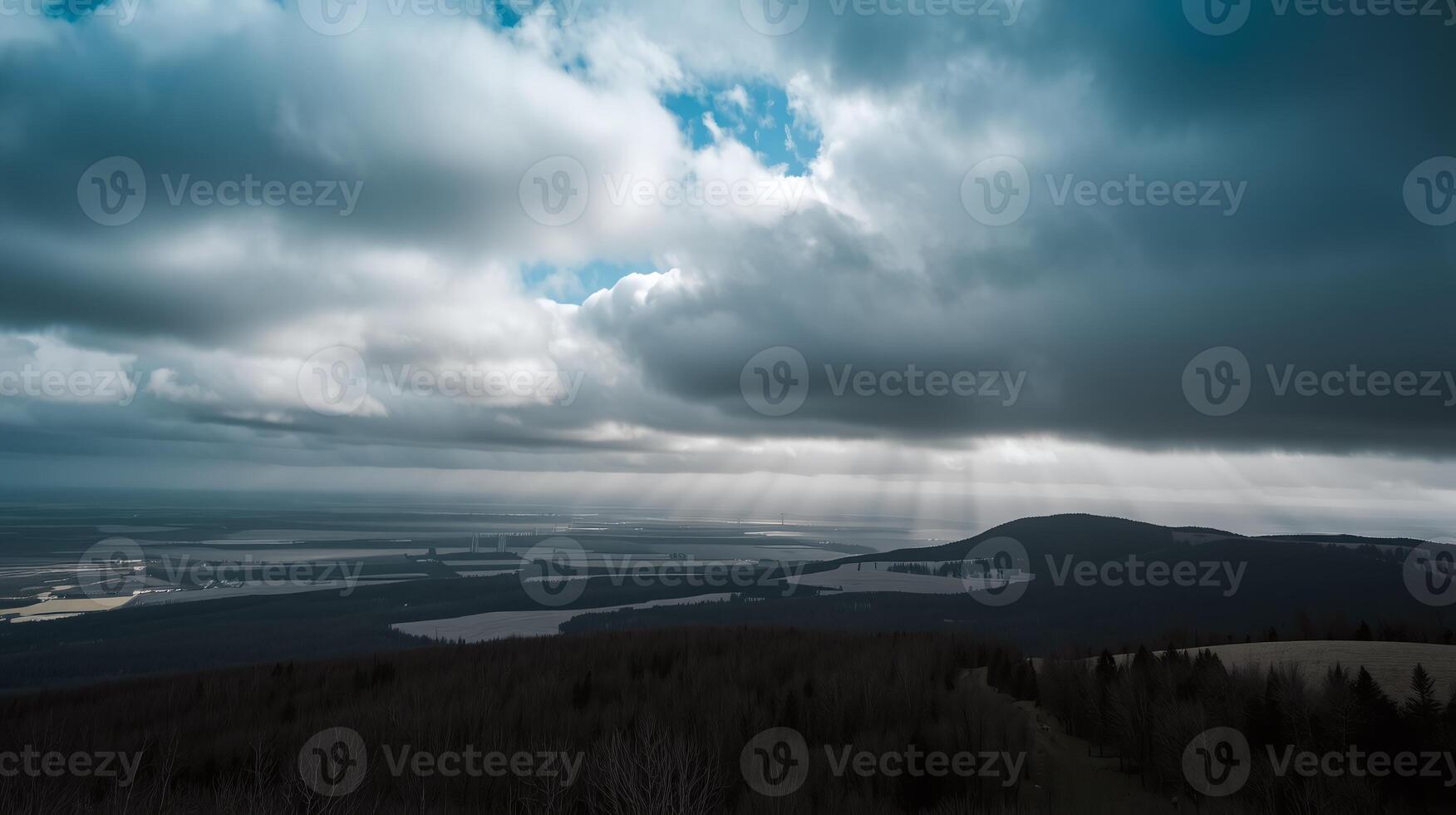 Amidst dense clouds, sunlight pierces through, illuminating vast, tranquil landscapes below. photo