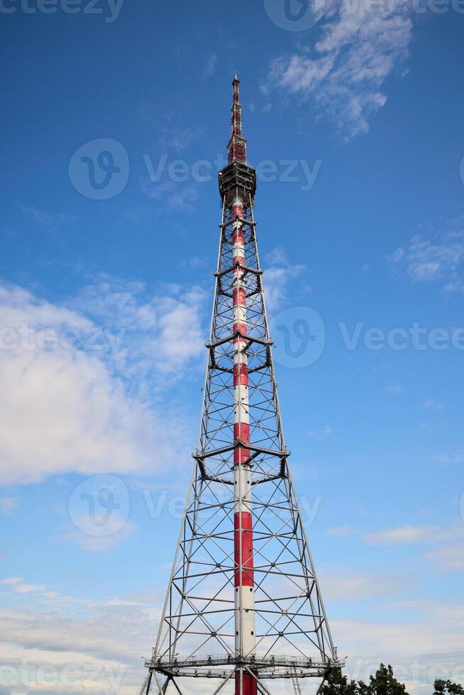 A Tall Communication Tower Positioned Dramatically Against a Bright Blue Sky Above photo