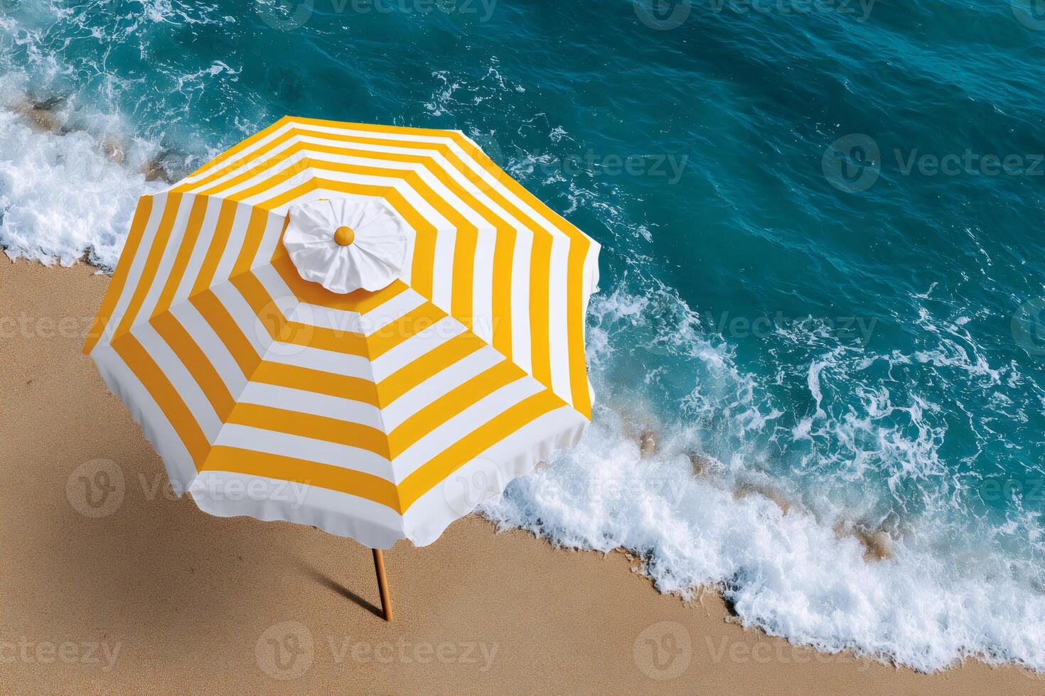 Yellow and white beach umbrella standing on golden sand near turquoise sea waves photo