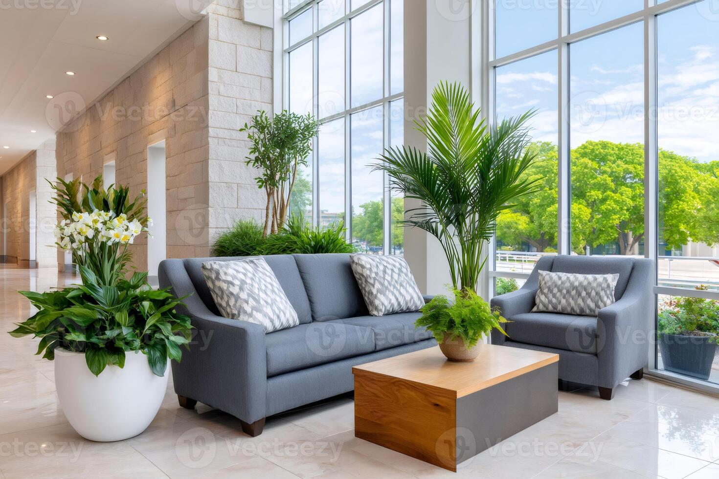 Comfortable waiting area with sofa and armchair near large windows illuminating plants photo