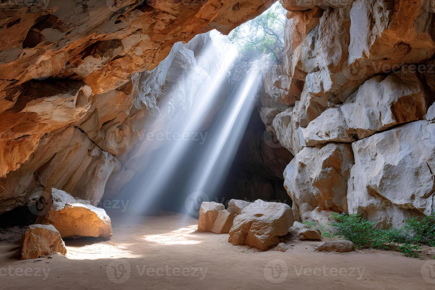 Sun rays illuminating cave with rocks and sand photo