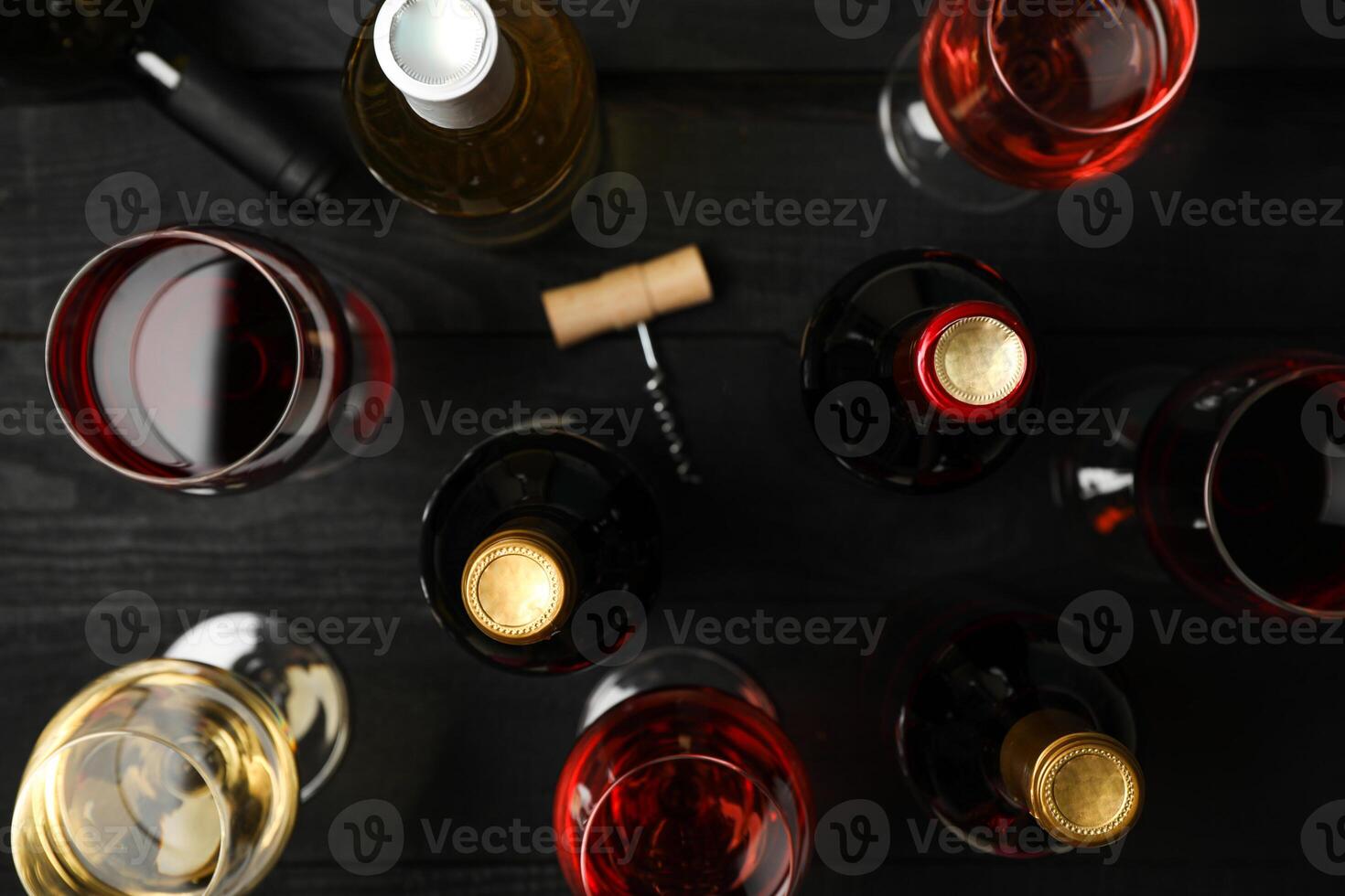 Bottles and glasses with different wine on wooden background, top view photo