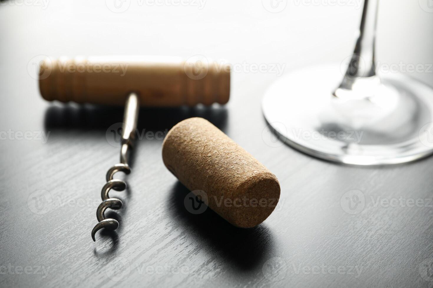 Corkscrew, cork and wine glass on dark table, close up photo