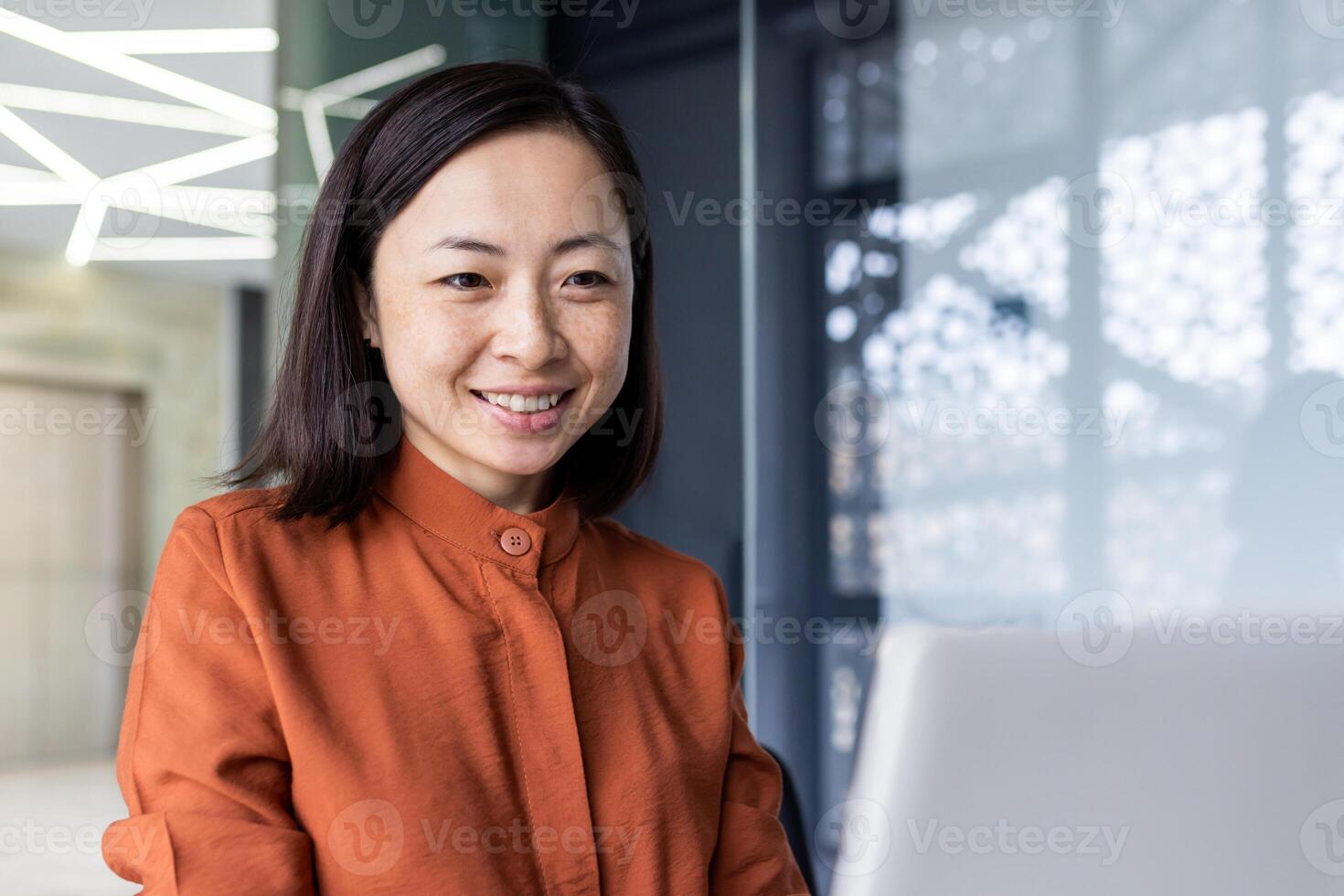 Young beautiful and successful businesswoman closeup at workplace working inside office, asian financier smiling and looking at laptop, female programmer student intern sitting at desk satisfied. photo