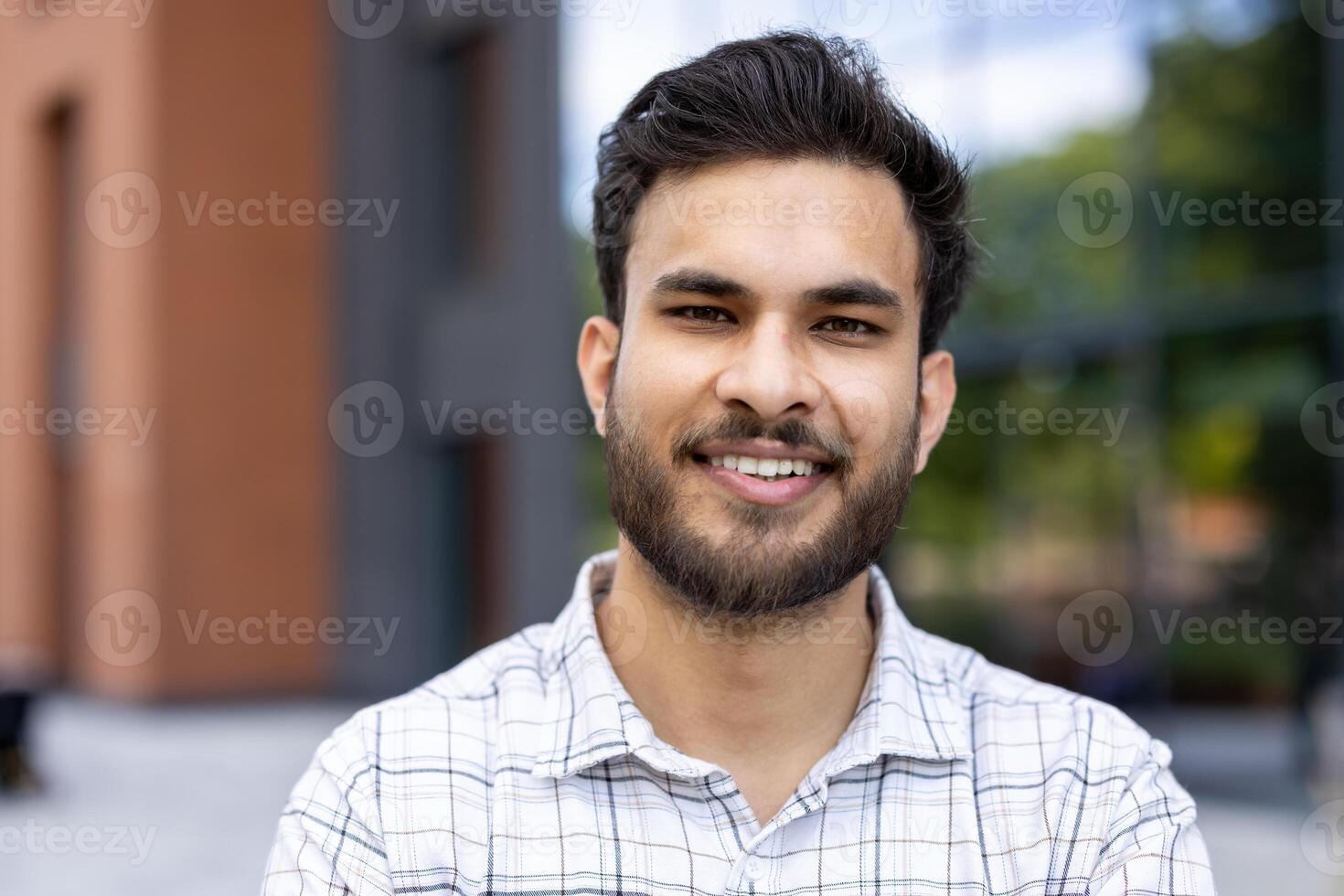 A young, smiling student poses for the camera, showcasing a confident and friendly expression, outdoors with a building. photo
