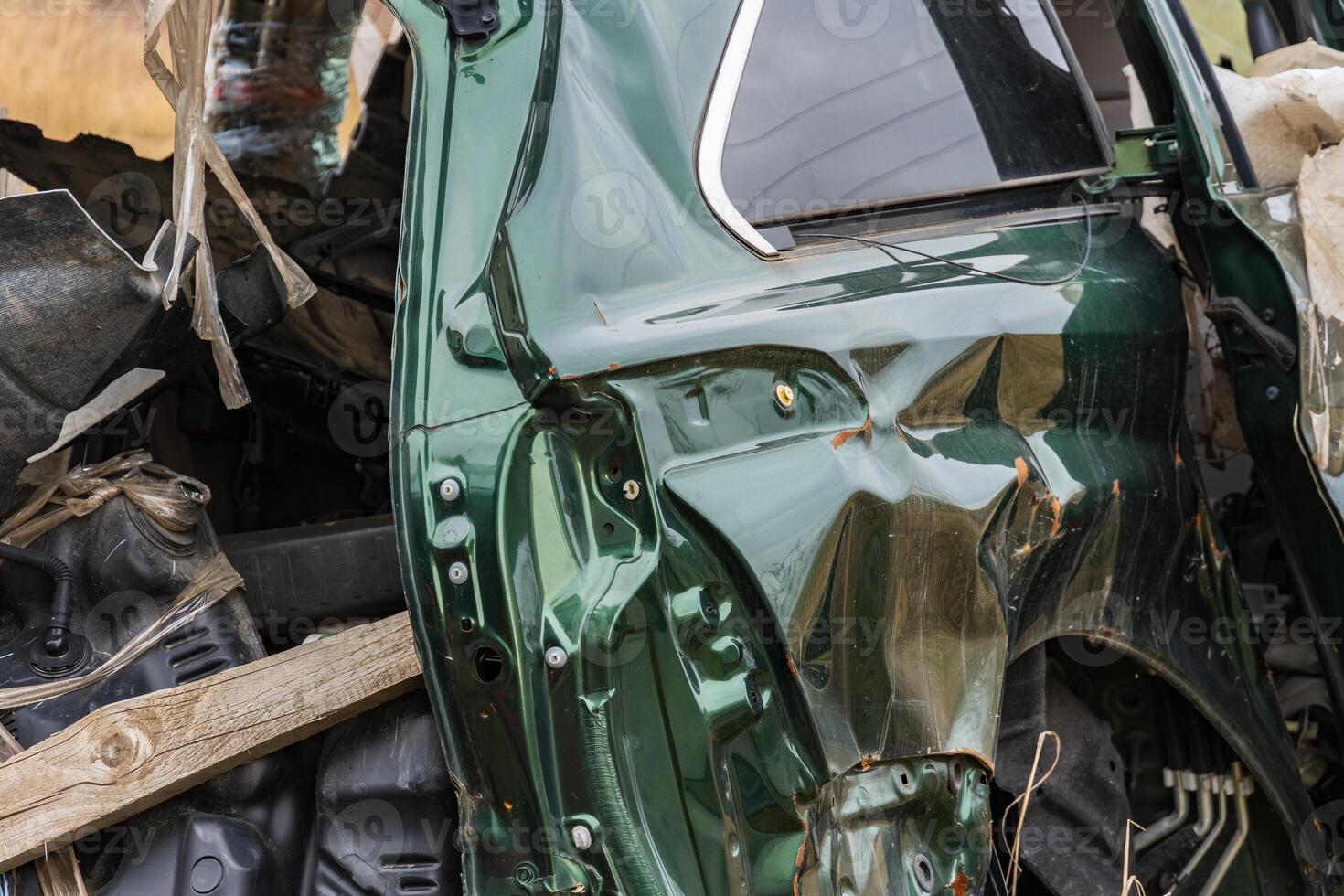 A wrecked car lies in a rural location, showcasing extensive damage to the side panel and highlighting transportation dangers and insurance concerns photo