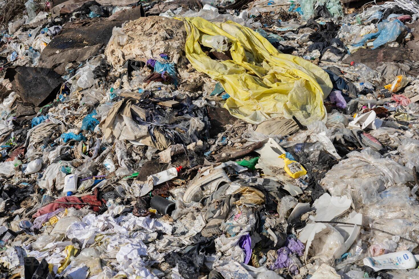A landfill overflowing with discarded plastic, clothes, and garbage highlights the urgent need for better waste management and recycling practices photo