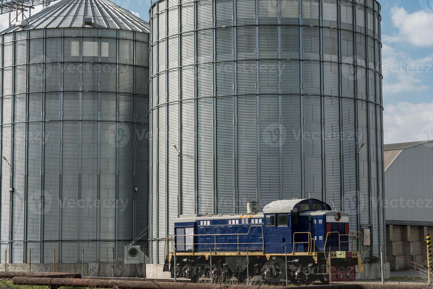 Heavy machinery and train prepare for efficient grain storage in a farming area during the harvesting season, showcasing agricultural infrastructure photo