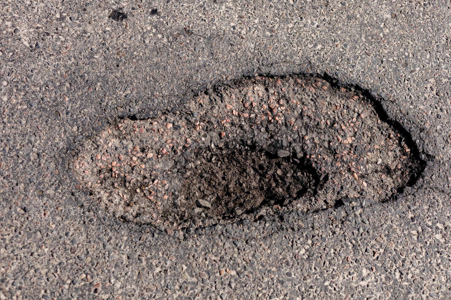 Large hole in the asphalt is evident on the highway, indicating significant damage that requires urgent repair to ensure safety for all vehicles photo