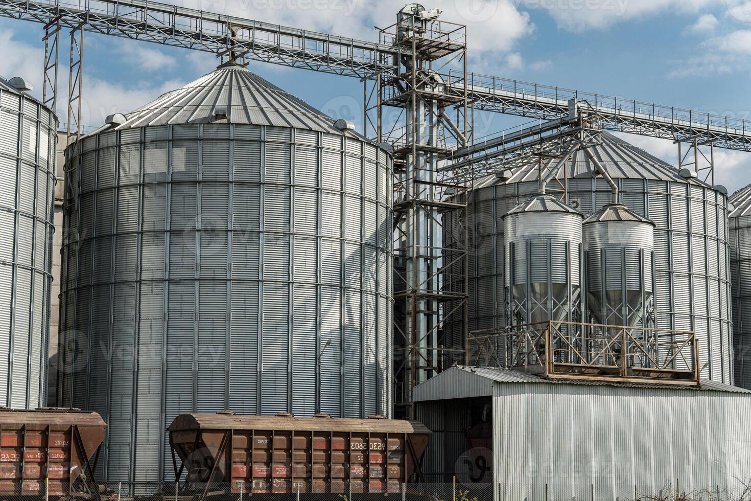 Large silos stand at an agricultural facility, storing harvested grain and crops in a rural area under a bright sky photo