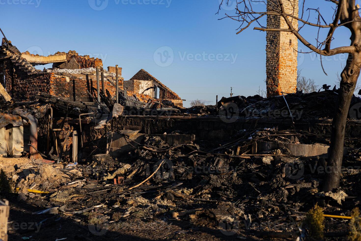 Ruins of a burned building reveal charred remains and debris, illustrating the impact of a recent fire in a rural setting during daylight photo