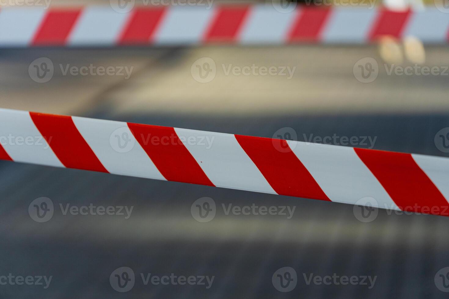 Bright red and white caution tape signals a restricted area at a community event, with blurred figures in the background enjoying the festivities photo